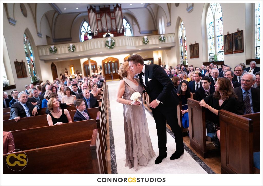 groom kissing his mom walking down the aisle at The Basilica of St. Mary Church in old town Alexandria, Virginia photography by Connor Studios 