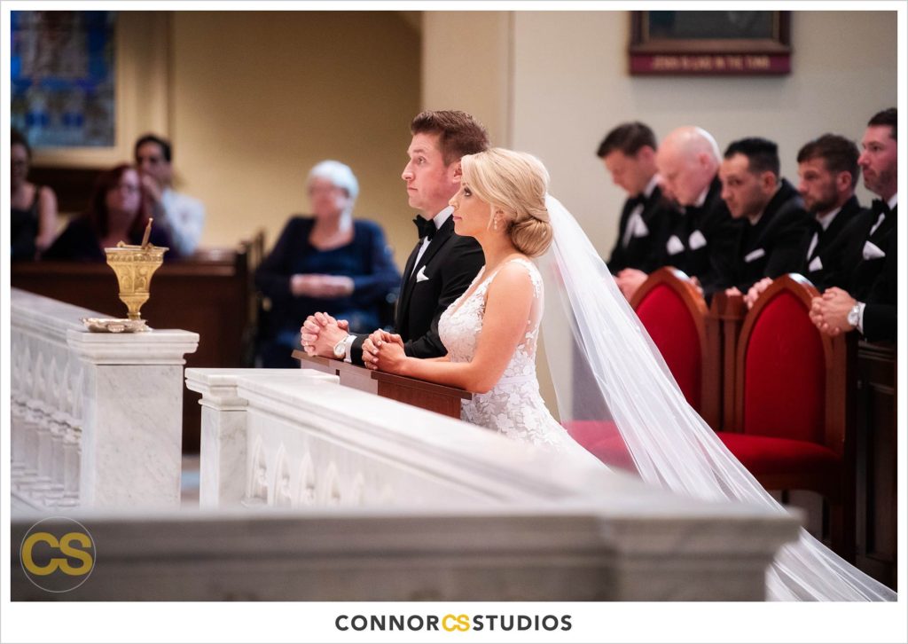 wedding ceremony with bride and groom praying at The Basilica of St. Mary Church in old town Alexandria, Virginia photography by Connor Studios 