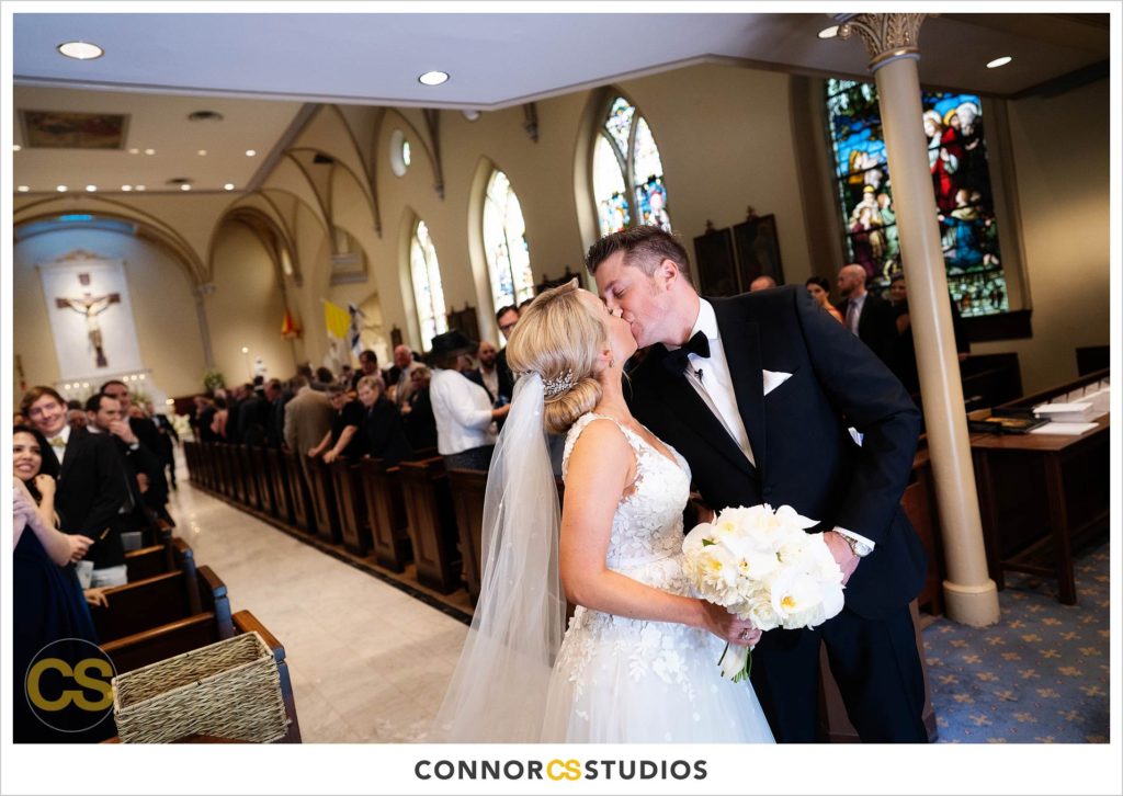 wedding ceremony and recessional with bride and groom kissing at The Basilica of St. Mary Church in old town Alexandria, Virginia photography by Connor Studios 