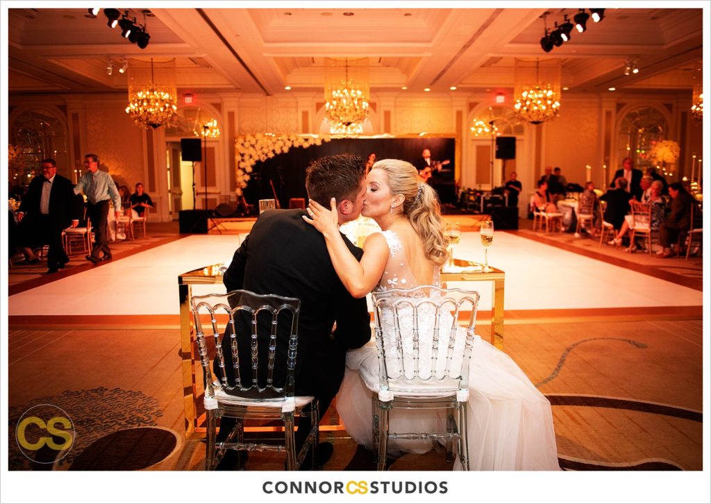 bride and groom kissing during luxury wedding with candles and gold colors in the ballroom at Fairmont Hotel in Washington, DC photography by Connor Studios 