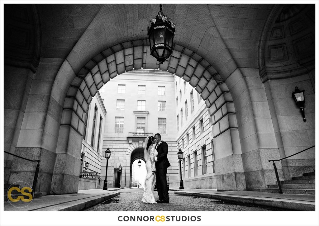 black and white photograph of bride and groom under the arches at the Andrew W. Mellon Auditorium in Washington, DC by Connor Studios