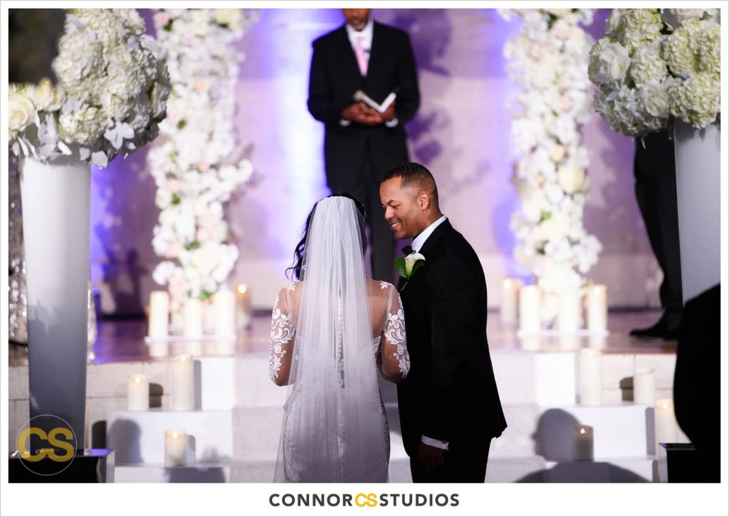 bride and groom entering wedding at the Andrew W. Mellon Auditorium in Washington, DC by Connor Studios surrounded by tall white floral arrangements
