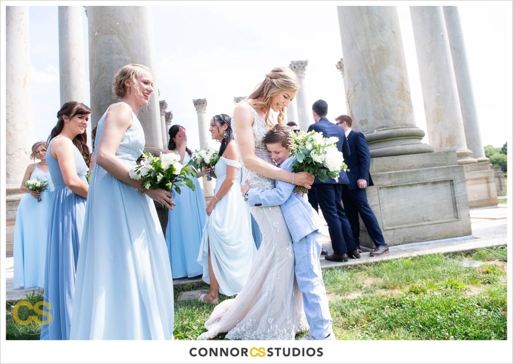 photograph of bride, bridesmaids in baby blue dresses and cute ring bearer on their wedding day for portraits at the National Capitol Columns at the national arboretum in washington, dc by connor studios