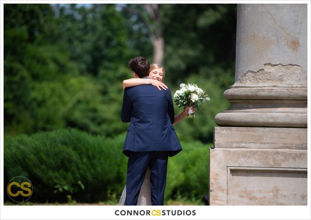 photograph of bride and groom hugging at first look on their wedding day at the National Capitol Columns at the national arboretum in washington, dc by connor studios