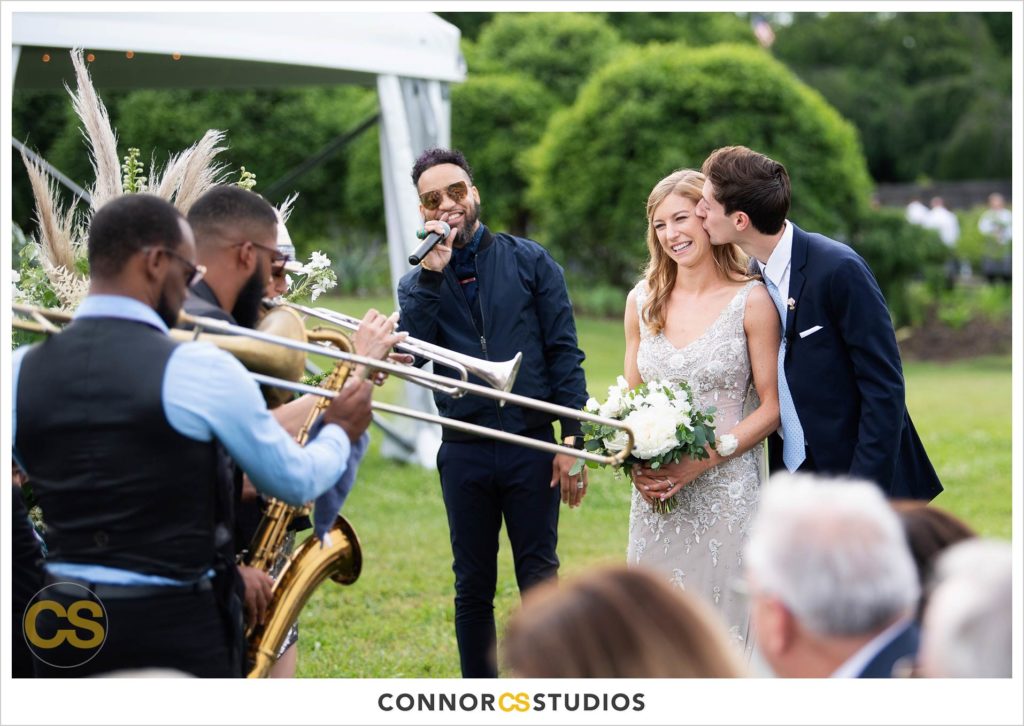 bride and groom being surprised with song walking down aisle during outdoor summer wedding ceremony at the national arboretum in washington, dc by connor studios