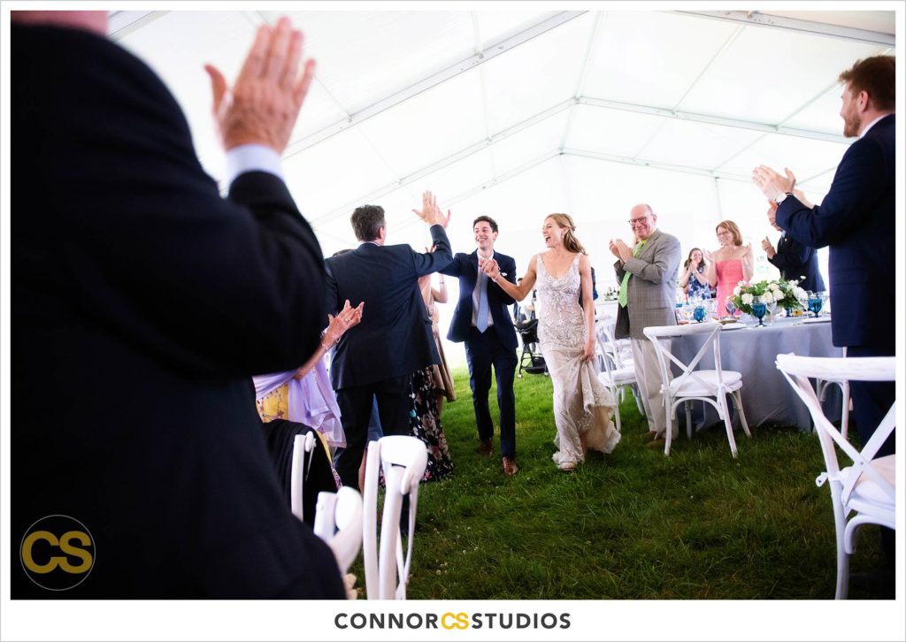 bride and groom entering large tented outdoor summer wedding reception at the national arboretum in washington, dc by connor studios