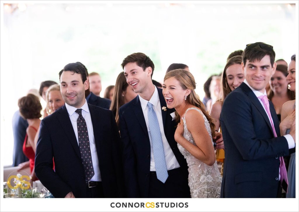 bride and groom laughing during  speeches at large tented outdoor summer wedding reception at the national arboretum in washington, dc by connor studios