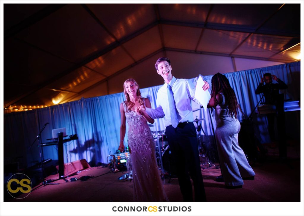 bride and groom laughing during  speeches at large tented outdoor summer wedding reception at the national arboretum in washington, dc by connor studios