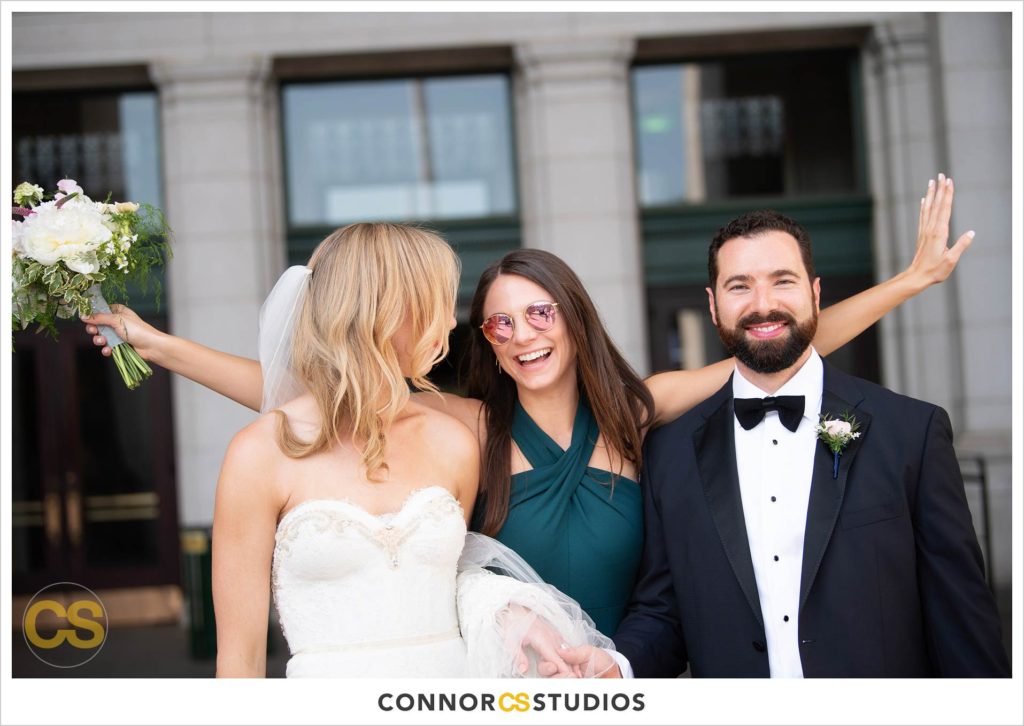 bride and groom with bridesmaid in green dress during portraits at union station in washington, dc by connor studios