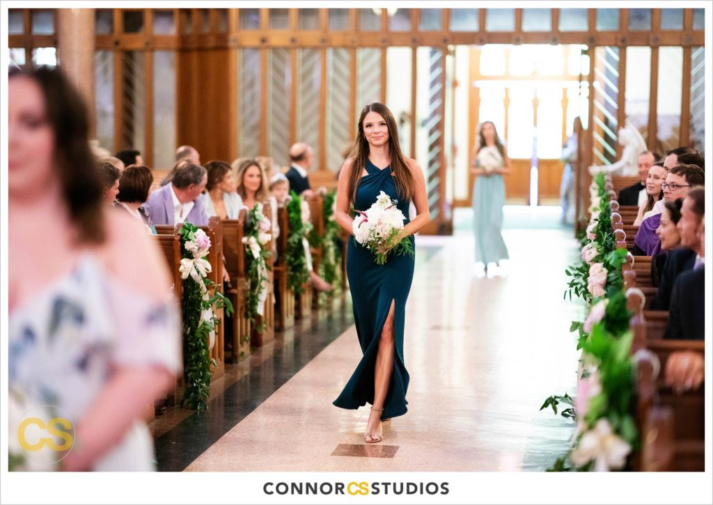 bridesmaid walking down the aisle in green dress with slit on leg during wedding at st. patrick's catholic church in washington, dc by connor studios