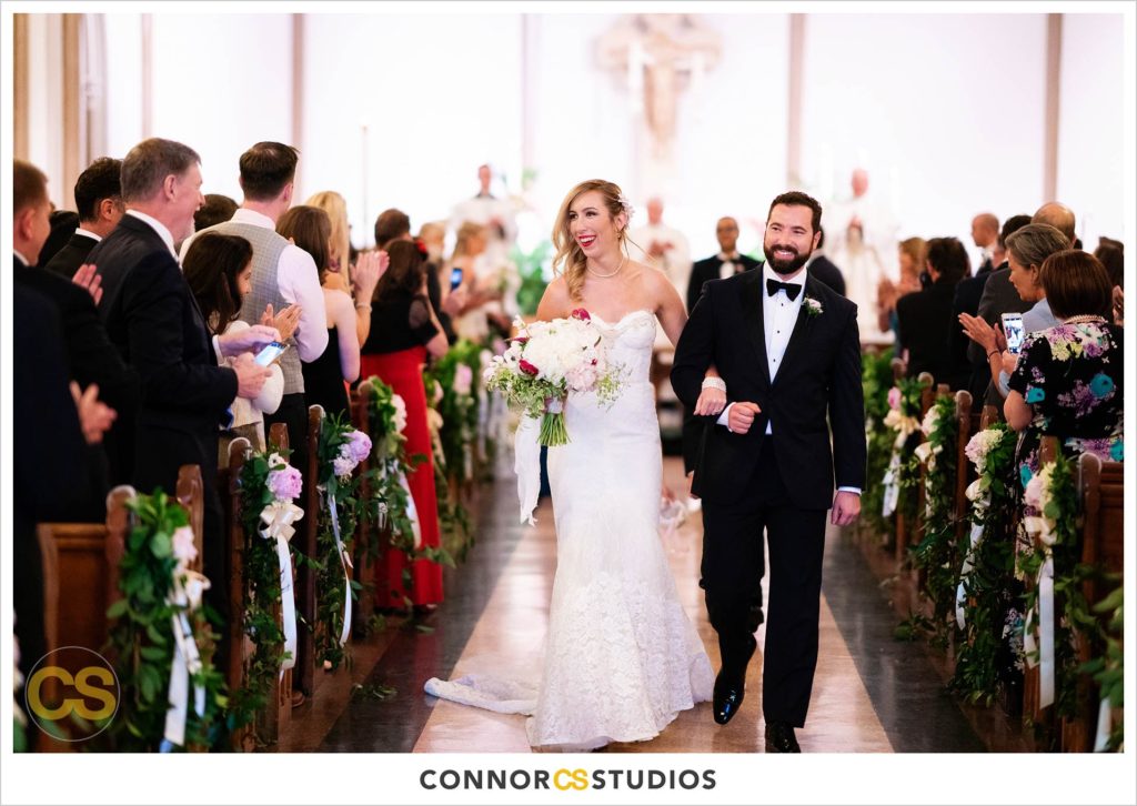 bride and groom walking down the aisle during recessional at their wedding at st. patrick's catholic church in washington, dc by connor studios