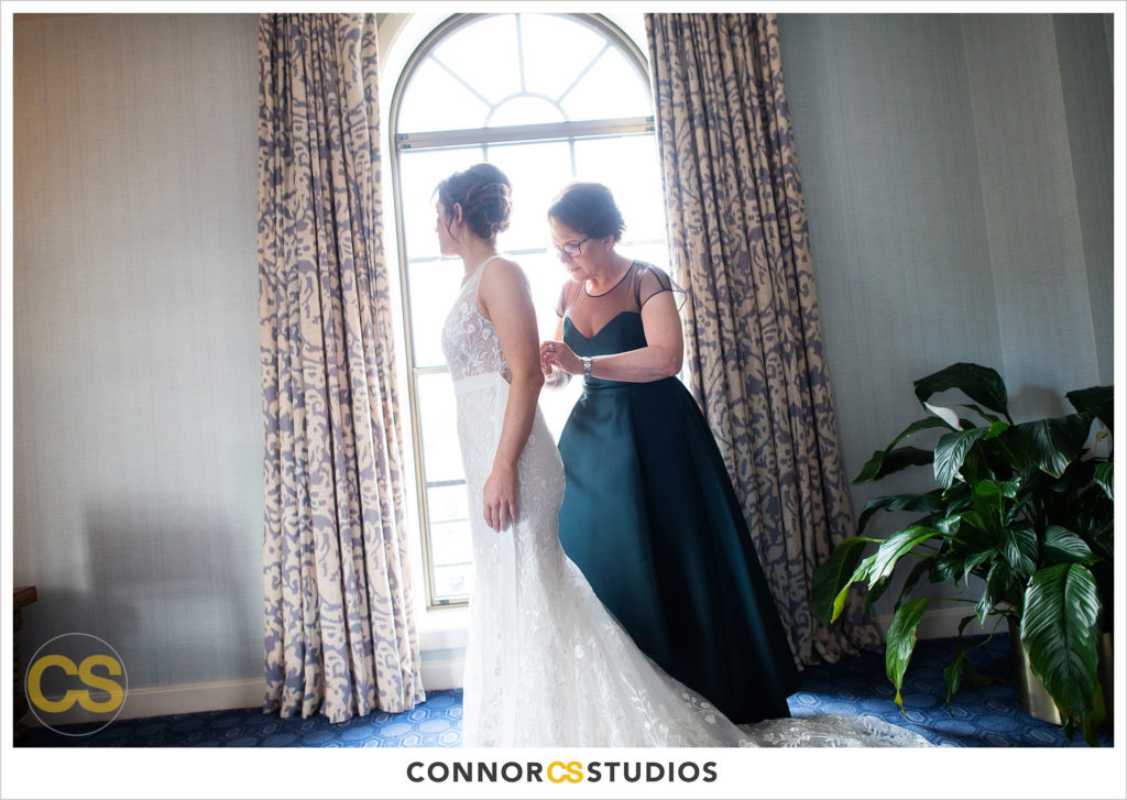 bride's mom helping her into her wedding dress at the st regis hotel in washington, dc by connor studios