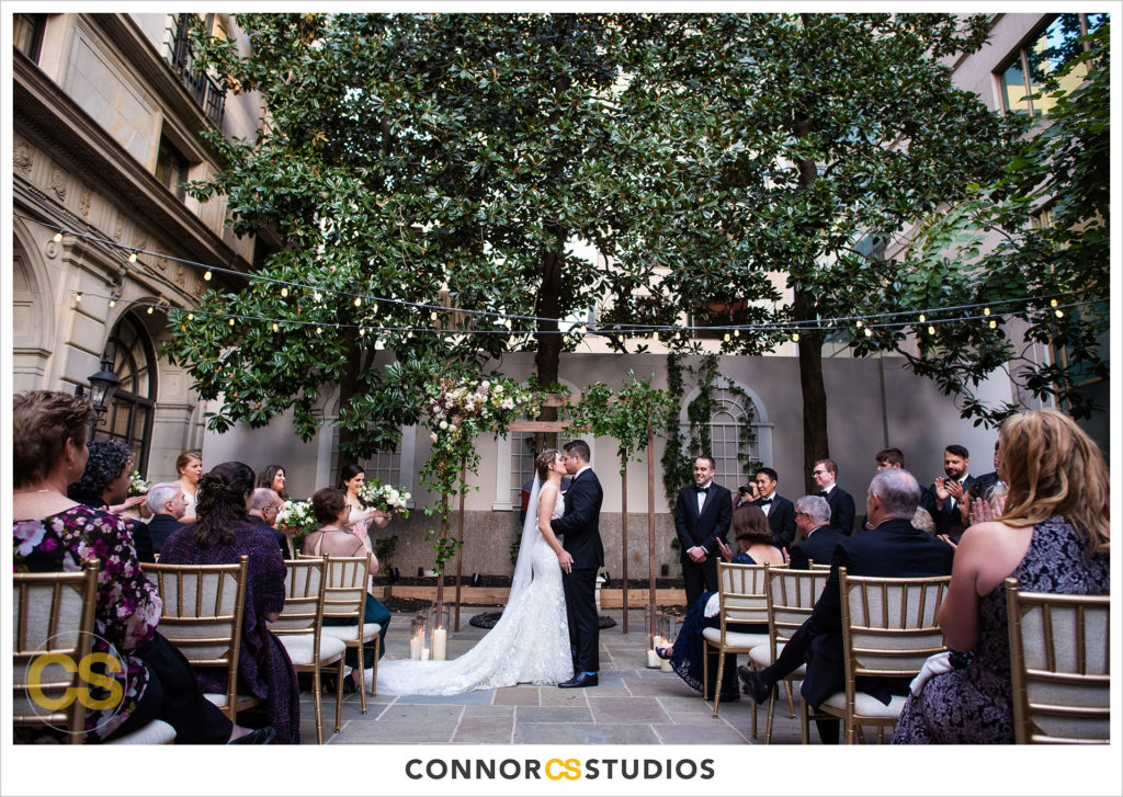 first kiss during outdoor wedding on the astor terrace at the st regis hotel in washington, dc by connor studios